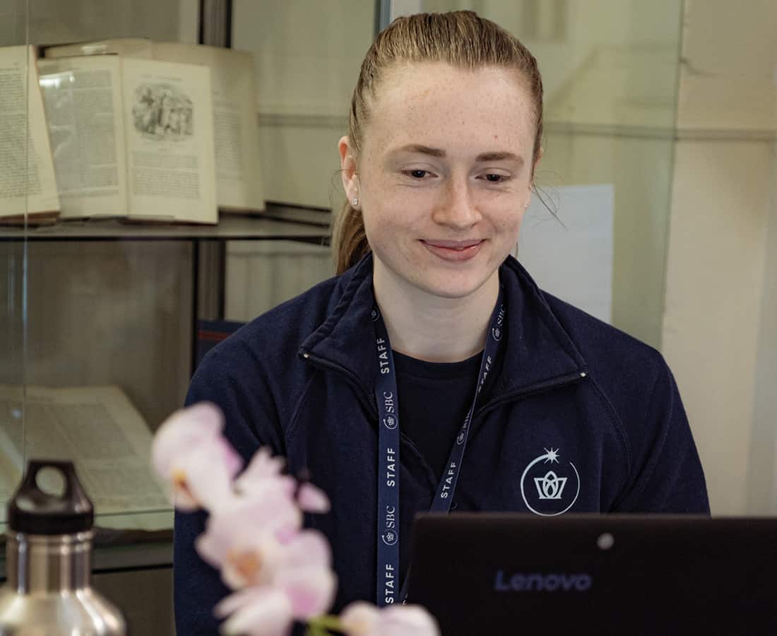 Summer Boarding Courses Office Co-ordinator sat at her desk with a laptop