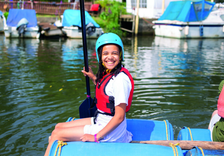Bright happy girl enjoying summer water sports during a summer boarding course on a boat, wearing a helmet and life jacket.