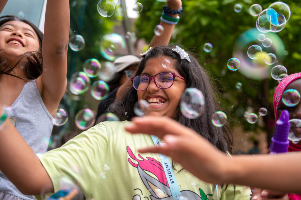 Children enjoying bubbles at summer boarding camp in outdoor setting.
