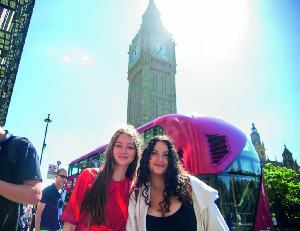 Bright young students sightseeing in London with iconic Big Ben and red double-decker bus.