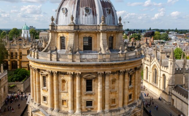 Historic Oxford University Radcliffe Camera, an iconic building in summer with students and tourists.